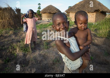 Une jeune fille et son petit frère dans leur maison à l'extérieur, l'Ouganda Amuria, Afrique de l'Est. Banque D'Images