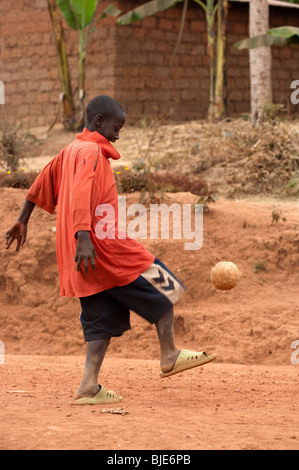 Jeune garçon jouant au football dans la rue du village, près de Kigali, Rwanda Banque D'Images