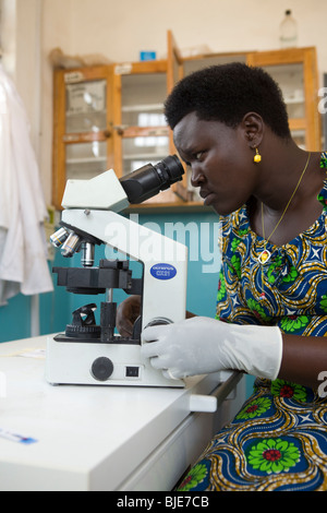 Un technicien de laboratoire dans l'Ouganda Amuria, examine le sang d'un patient pour des signes de paludisme. Banque D'Images