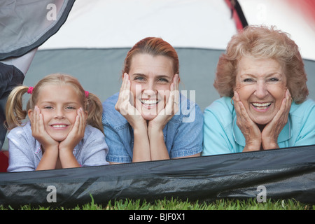 Mère, fille et petite-fille s'appuyer sur les coudes, tente de sourire Banque D'Images