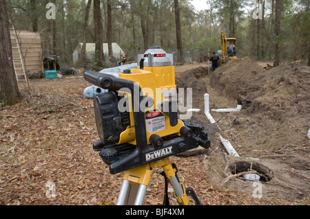 L'installation du nouveau système septique drainfield niveau contrôle l'angle pour un bon drainage avec DeWalt niveau laser sur un trépied Banque D'Images