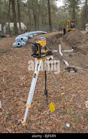 L'installation du nouveau système septique drainfield niveau contrôle l'angle pour un bon drainage avec DeWalt niveau laser sur un trépied Banque D'Images