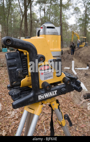 L'installation du nouveau système septique drainfield niveau contrôle l'angle pour un bon drainage avec DeWalt niveau laser sur un trépied Banque D'Images