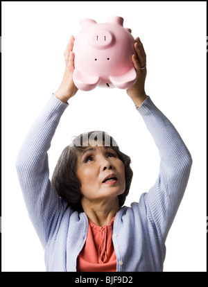 Senior woman shaking piggy bank Banque D'Images