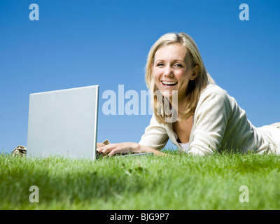 Femme couchée sur l'herbe à l'aide d'un ordinateur portable Banque D'Images