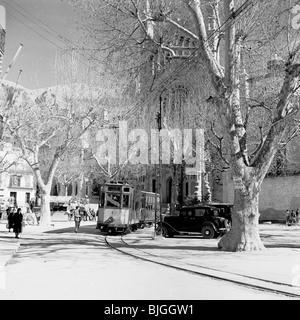 Le tram s'arrête dans une ville espagnole dans les années 50 dans ce tableau historique par J Allan l'argent comptant. Banque D'Images