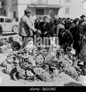 Années 1950. Dans ce tableau historique par J Allan en argent comptant, un commerçant du marché espagnol dans la pipe de la rue, montre aux clients ses choux. Banque D'Images