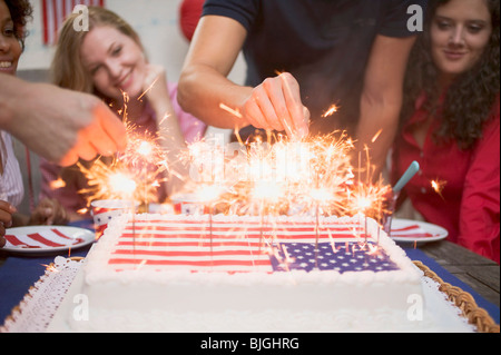 Éclairage mains cierges sur un gâteau (4 juillet, USA) - Banque D'Images