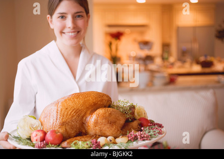 Jeune femme de servir la dinde rôtie sur le plateau - Banque D'Images