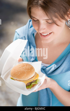 Jeune femme avec cheeseburger hors des portes - Banque D'Images