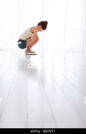 Femme pesant sur un pèse-personne Banque D'Images