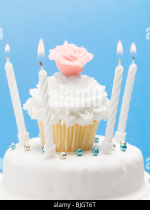 Gâteau d'anniversaire avec décoration de muffins, massepain et bougies - rose Banque D'Images