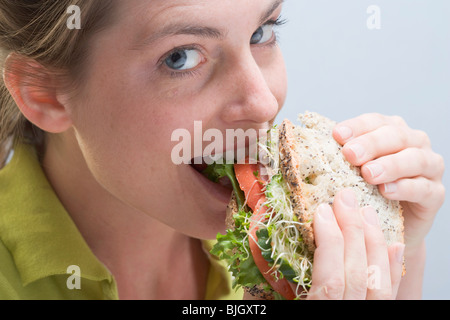 Femme mordre dans un sandwich avec plaisir - Banque D'Images