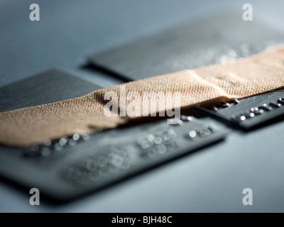 Carte de crédit réduit de moitié avec une bande-aide maintenant à l'ensemble Banque D'Images