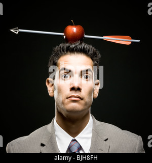 Businessman avec une pomme sur la tête qui a été tourné avec une flèche Banque D'Images