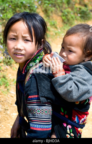 Fille du groupe minoritaire noir de H'Mong avec un bébé dans un papoose, Muong OA Valley, Sapa, nord du Vietnam Banque D'Images