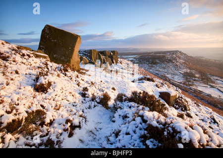 Curbar Edge illuminée par les derniers rayons du soleil couchant dans le Peak District à la suite de neige en hiver Banque D'Images