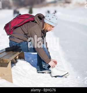 Femme attacher ses patins à glace à l'extérieur, l'Assiniboine River Trail, Winnipeg, Manitoba, Canada. Banque D'Images