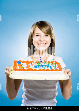 Fille regardant la caméra tenant un gâteau d'anniversaire Banque D'Images