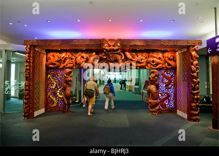 L'Aéroport International d'Auckland porte des arrivées avec les Maoris sculpture en bois accueillant voyageurs, Auckland, Nouvelle-Zélande Banque D'Images