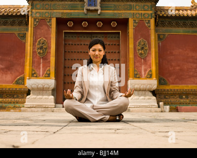 Businesswoman sitting cross legged outdoors méditer Banque D'Images