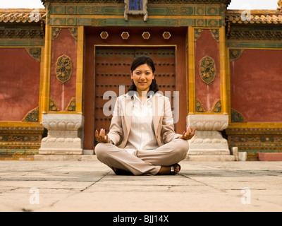 Businesswoman sitting cross legged outdoors méditer Banque D'Images