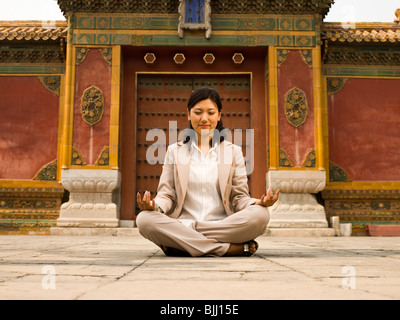 Businesswoman sitting cross legged outdoors méditer Banque D'Images