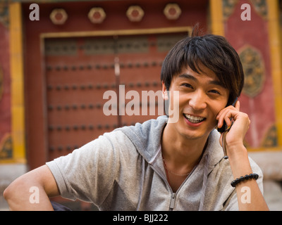 Teenage boy outdoors with cell phone smiling Banque D'Images