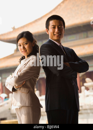 Businessman and woman standing with arms crossed et dos avec pagoda en arrière-plan Banque D'Images