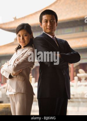 Businessman and woman standing with arms crossed et dos avec pagoda en arrière-plan Banque D'Images