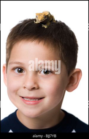 Gros plan du garçon avec lizard on head smiling Banque D'Images