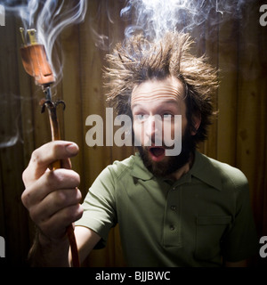 L'homme après un choc électrique avec prise électrique et la fumée Banque D'Images