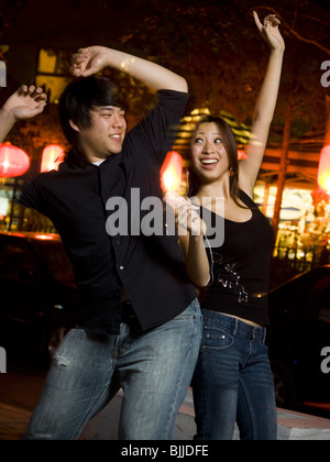 Couple listening to mp3 player outdoors dancing and smiling Banque D'Images