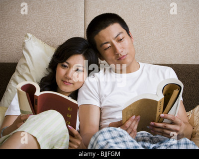 Couple dans le lit se blottir et de la lecture Banque D'Images