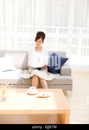 Woman Reading magazine on sofa in living room