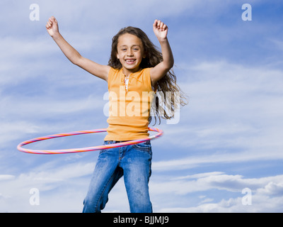 Girl Playing with hula hoop outdoors laughing Banque D'Images