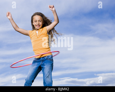 Girl Playing with hula hoop outdoors laughing Banque D'Images