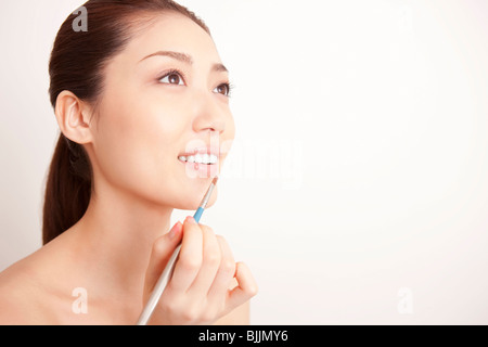 Young woman applying lipstick Banque D'Images