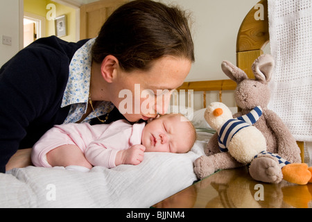 Mère embrassant / baisers dormir / sommeil bébé nouveau-né, sur le lit / lit bébé. Banque D'Images