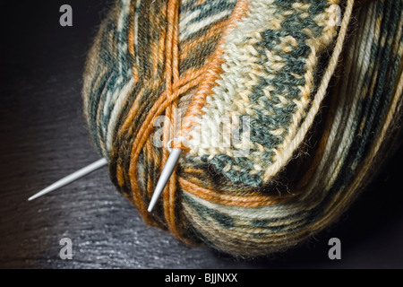 Le tricot, la balle de laine et des aiguilles à tricoter sur un fond d'ardoise Banque D'Images