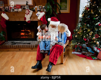 Garçons assis sur les genoux du Père Noël au moment de Noël. Banque D'Images