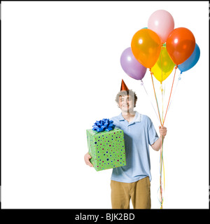 Homme avec party hat holding balloons et boîte-cadeau Banque D'Images