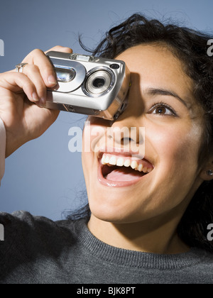 Femme de prendre une photo avec appareil photo numérique smiling Banque D'Images