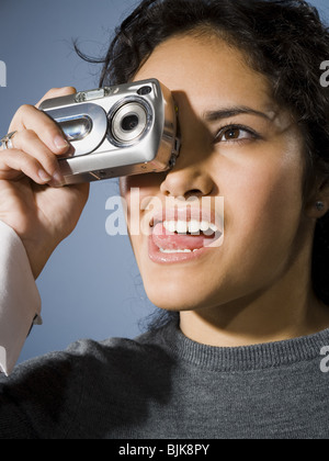 Femme de prendre une photo avec appareil photo numérique smiling Banque D'Images