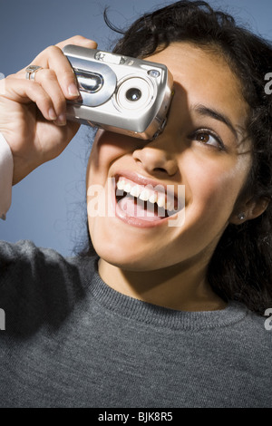 Femme de prendre une photo avec appareil photo numérique smiling Banque D'Images