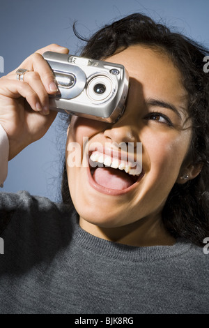 Femme de prendre une photo avec appareil photo numérique smiling Banque D'Images