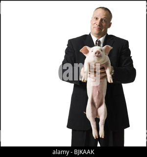 Businessman holding piglet Banque D'Images