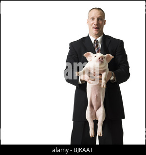 Businessman holding piglet Banque D'Images