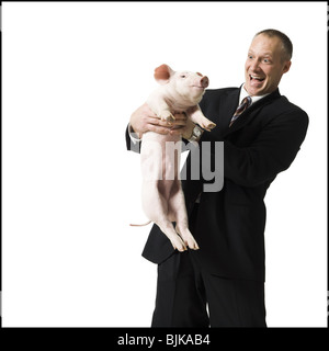 Businessman holding piglet Banque D'Images