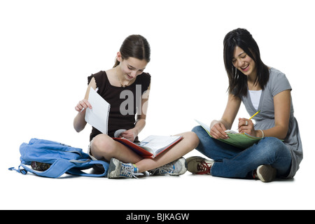 Deux filles sitting cross legged doing homework Banque D'Images